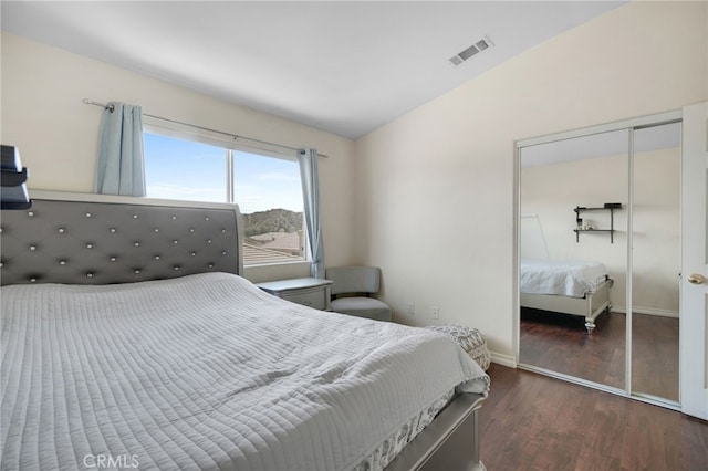 bedroom featuring baseboards, wood finished floors, vaulted ceiling, visible vents, and a closet