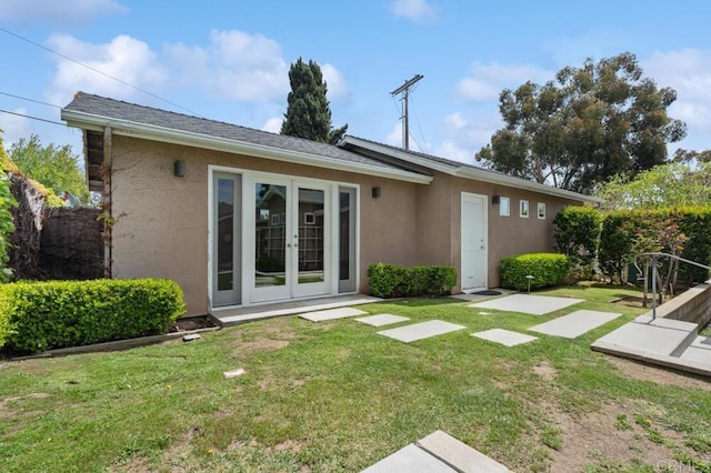 back of property with a lawn, stucco siding, and french doors