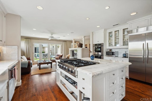 kitchen featuring backsplash, appliances with stainless steel finishes, open floor plan, glass insert cabinets, and recessed lighting