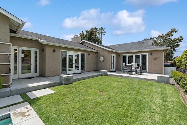 rear view of house featuring fence, stucco siding, a patio area, french doors, and a lawn