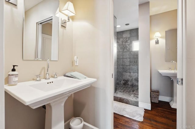 bathroom with baseboards, a tile shower, and wood finished floors