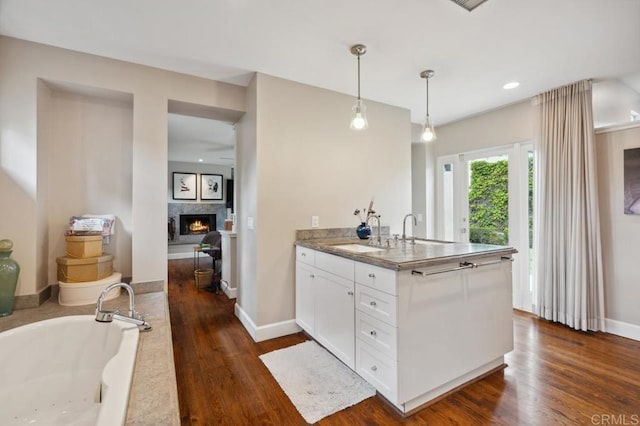 kitchen featuring pendant lighting, a sink, a peninsula, white cabinetry, and dark wood-type flooring