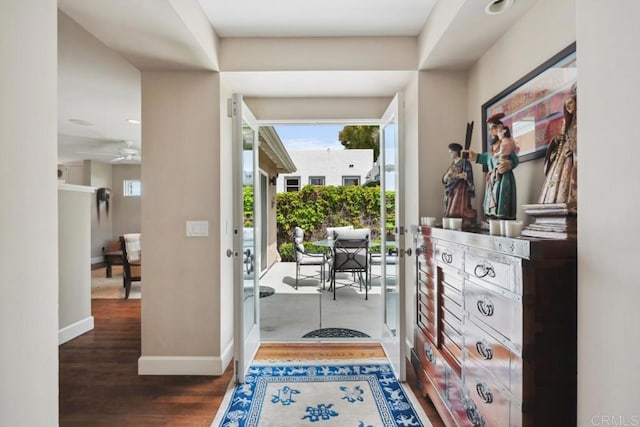 foyer entrance with baseboards, ceiling fan, and wood finished floors