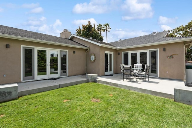 back of property with a yard, french doors, and stucco siding