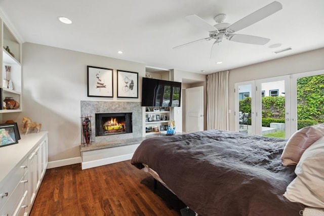 bedroom featuring visible vents, baseboards, dark wood-style floors, access to outside, and a premium fireplace