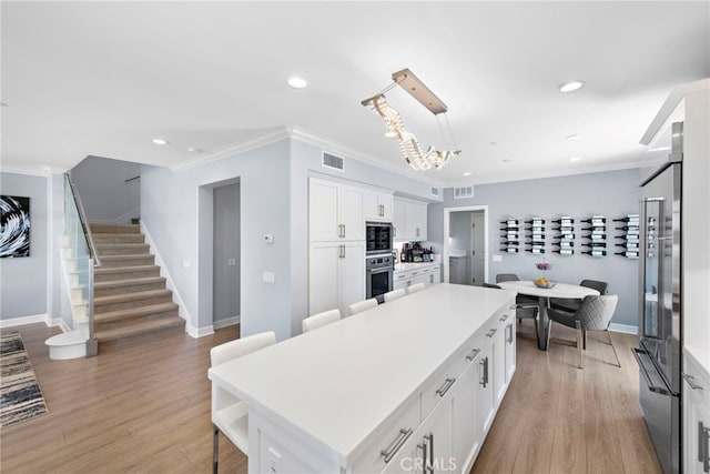207 Via Galicia, San Clemente, CA 92672 - kitchen with stainless steel appliances, white cabinets, a center island, light countertops, and ornamental molding