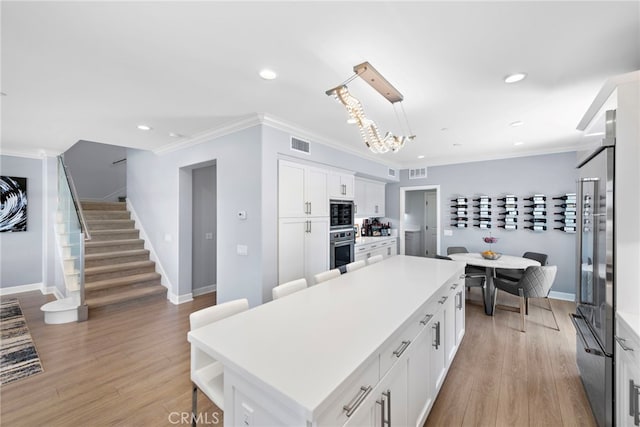 207 Via Galicia, San Clemente, CA 92672 - kitchen featuring stainless steel oven, a center island, white cabinets, light countertops, and crown molding