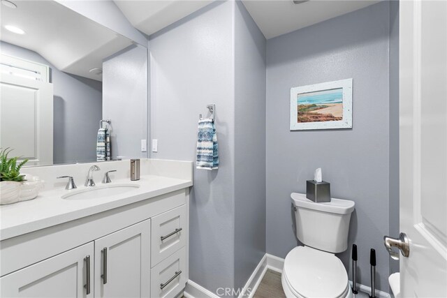 207 Via Galicia, San Clemente, CA 92672 - half bathroom featuring baseboards, vanity, toilet, and wood finished floors