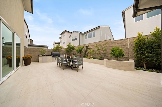 view of patio with area for grilling, outdoor dining area, and a fenced backyard
