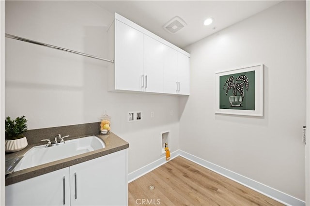clothes washing area featuring cabinet space, a sink, light wood-style floors, hookup for a washing machine, and baseboards
