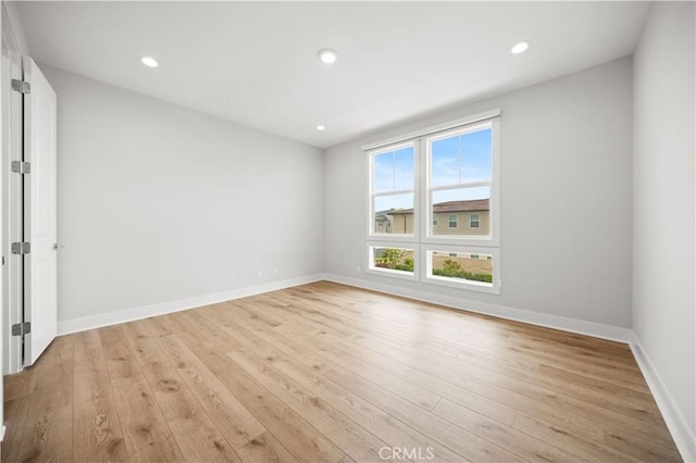 empty room with recessed lighting, light wood-style flooring, and baseboards