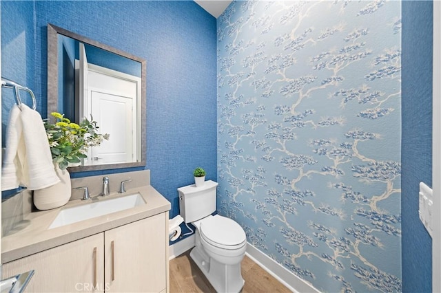 bathroom featuring toilet, baseboards, wood finished floors, and vanity
