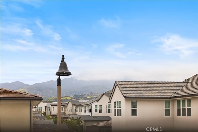 exterior space featuring a mountain view, stucco siding, a tile roof, and a residential view