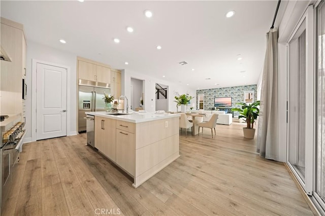 kitchen with a sink, modern cabinets, light brown cabinets, and open floor plan