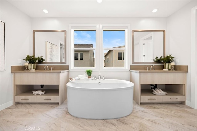 full bathroom featuring a freestanding bath, two vanities, a sink, and marble finish floor