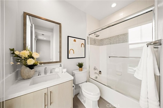 full bath featuring vanity, toilet, and shower / bath combination with glass door