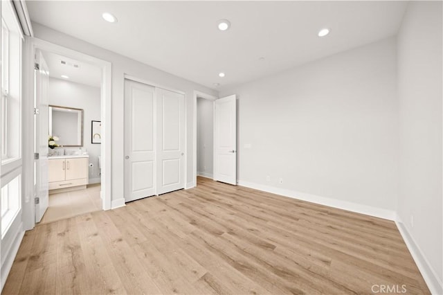 unfurnished bedroom featuring recessed lighting, baseboards, ensuite bathroom, and light wood-style floors