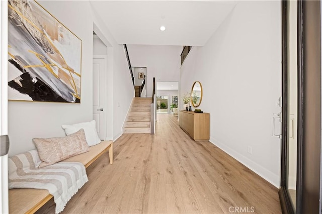 hallway with baseboards, recessed lighting, light wood-style flooring, and stairway