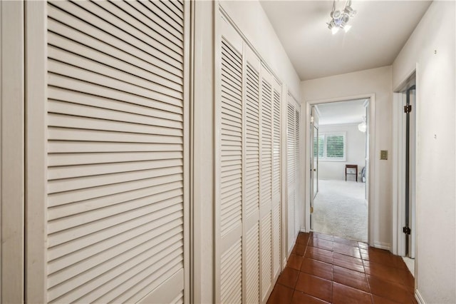 hall featuring dark tile patterned flooring and baseboards