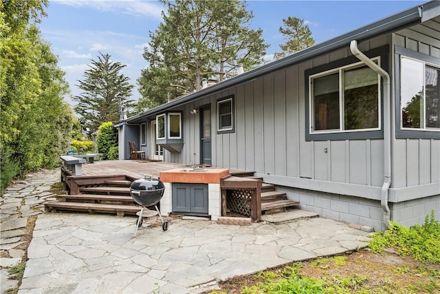 exterior space with board and batten siding, a patio area, and a deck