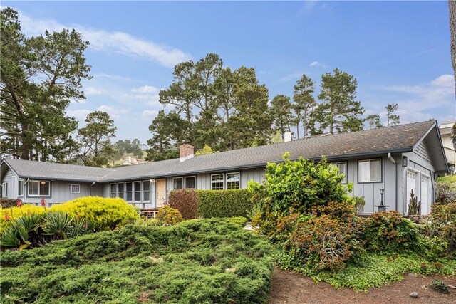 ranch-style house with a garage, board and batten siding, and a chimney