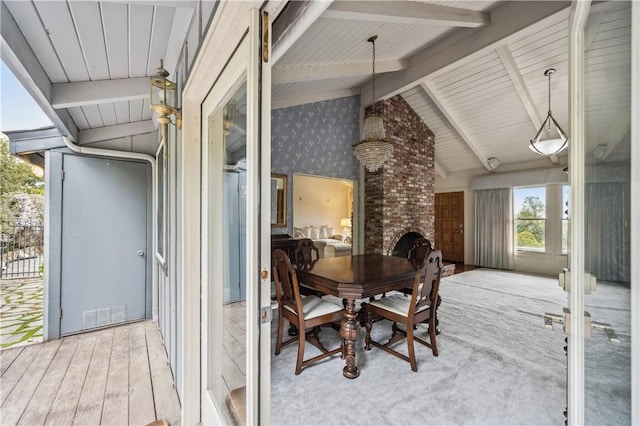 interior space with vaulted ceiling with beams, visible vents, wood finished floors, and a fireplace