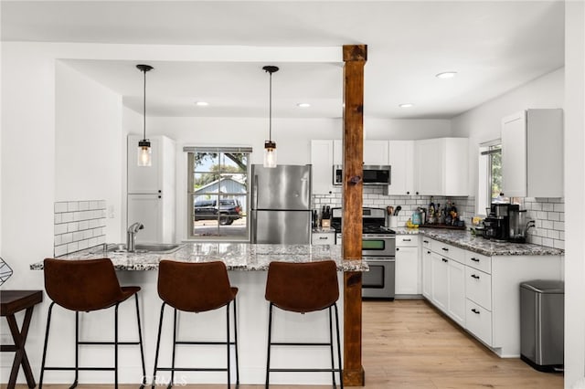 1326 Clock Ave, Redlands, CA 92374 - kitchen with a peninsula, a healthy amount of sunlight, a kitchen bar, a sink, and appliances with stainless steel finishes