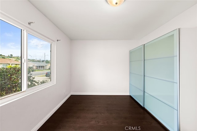 spare room with dark wood-style flooring and baseboards