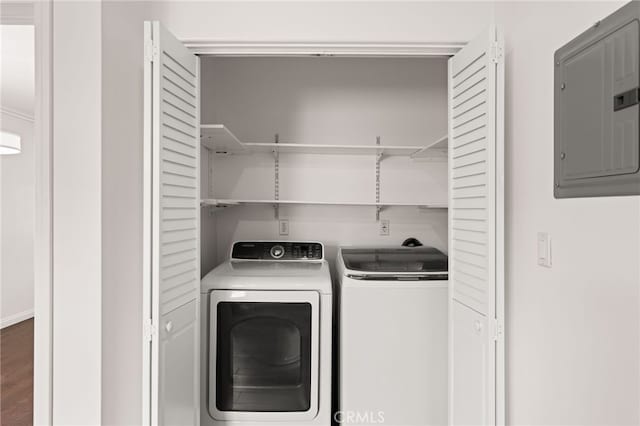 clothes washing area with electric panel, washing machine and dryer, wood finished floors, and laundry area