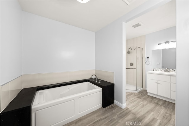 bathroom featuring a garden tub, visible vents, a stall shower, wood finished floors, and vanity