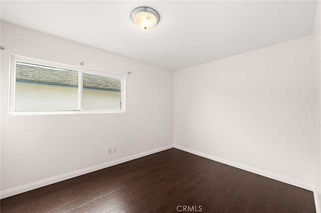 unfurnished room featuring baseboards and dark wood finished floors
