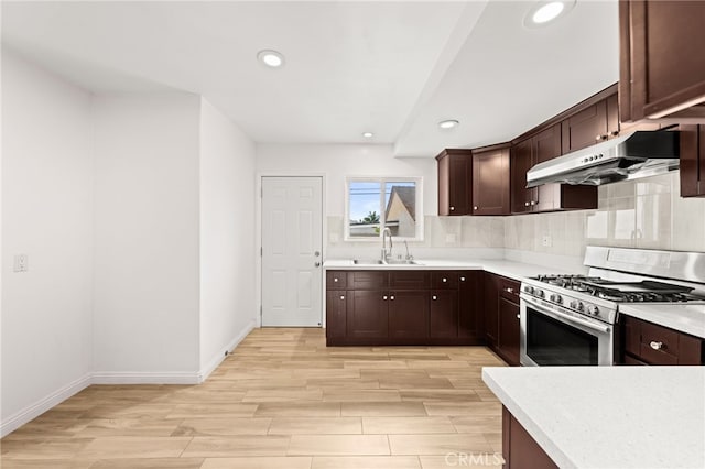 kitchen with under cabinet range hood, recessed lighting, stainless steel gas range oven, and light wood-style floors