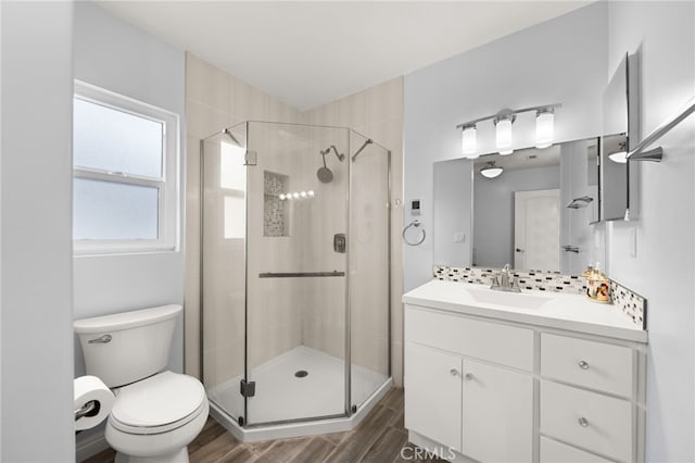 full bath featuring vanity, toilet, wood finished floors, and a stall shower