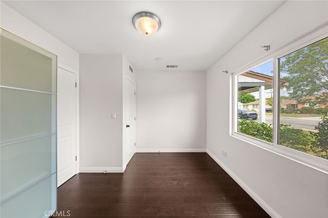 interior space with baseboards, wood finished floors, and visible vents