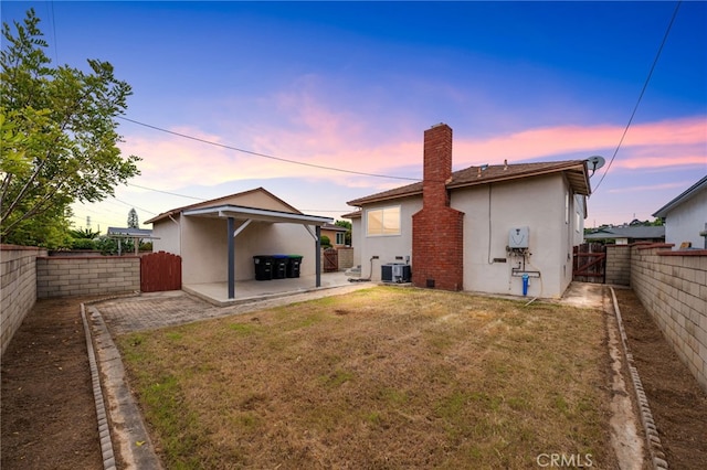 back of house at dusk with a patio, a fenced backyard, a lawn, and central AC unit