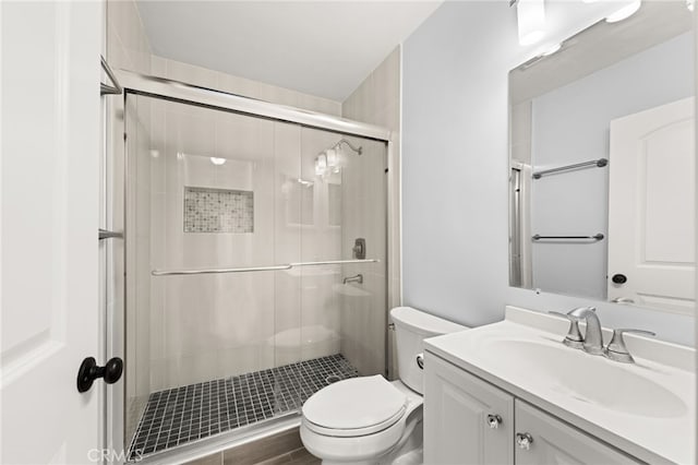 bathroom with toilet, a shower stall, and vanity