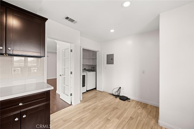 kitchen with electric panel, visible vents, washing machine and dryer, light wood-type flooring, and dark brown cabinets