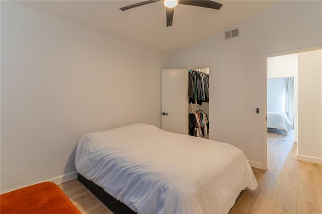 bedroom featuring visible vents, light wood-style floors, baseboards, and vaulted ceiling