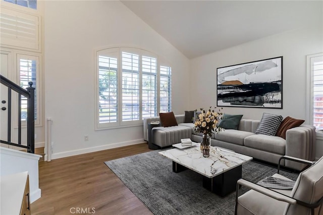 living room featuring high vaulted ceiling, plenty of natural light, stairs, and wood finished floors