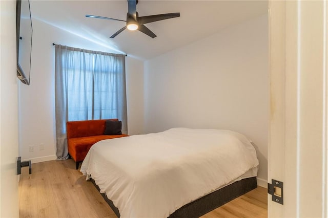 bedroom featuring baseboards, a ceiling fan, wood finished floors, and vaulted ceiling