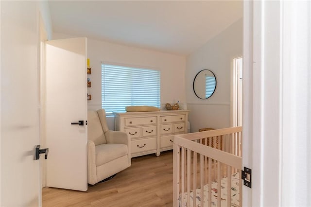 bedroom featuring light wood-type flooring and a nursery area