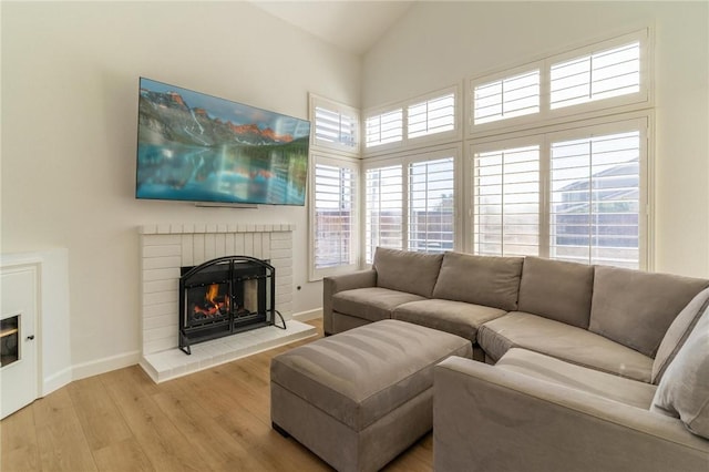 living room with baseboards, a brick fireplace, high vaulted ceiling, and wood finished floors