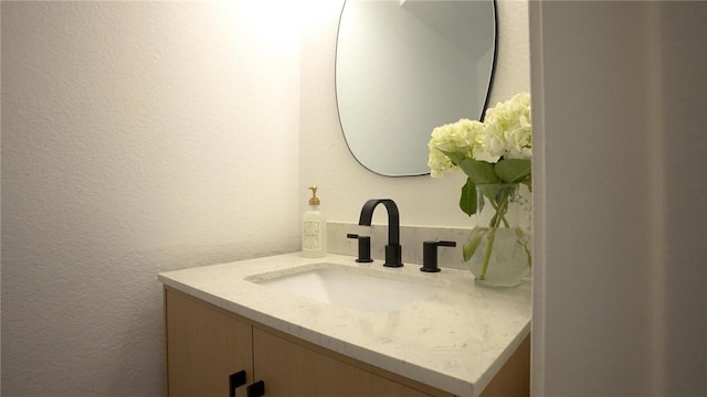 bathroom with a textured wall and vanity