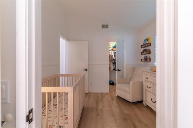 bedroom with light wood-style floors, lofted ceiling, a spacious closet, visible vents, and a closet