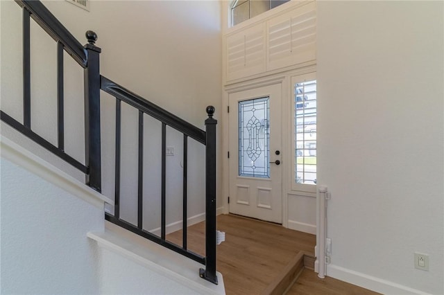 foyer featuring baseboards, stairs, and wood finished floors