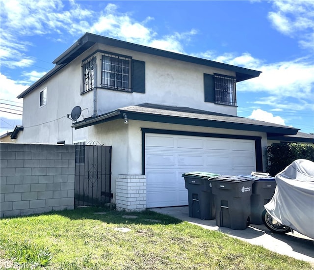 view of side of home with fence, stucco siding, brick siding, an attached garage, and a yard