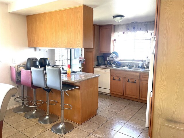 kitchen with a kitchen breakfast bar, dishwasher, a sink, light tile patterned floors, and a peninsula