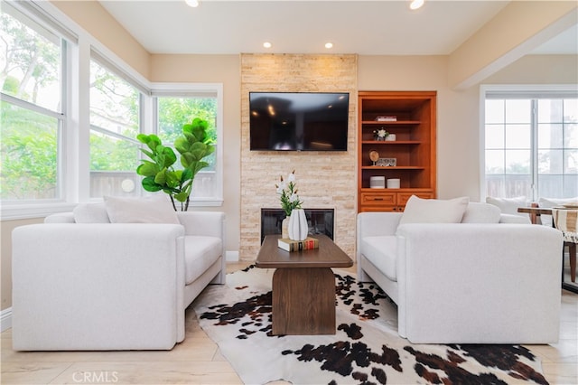 living room featuring recessed lighting, baseboards, and a stone fireplace