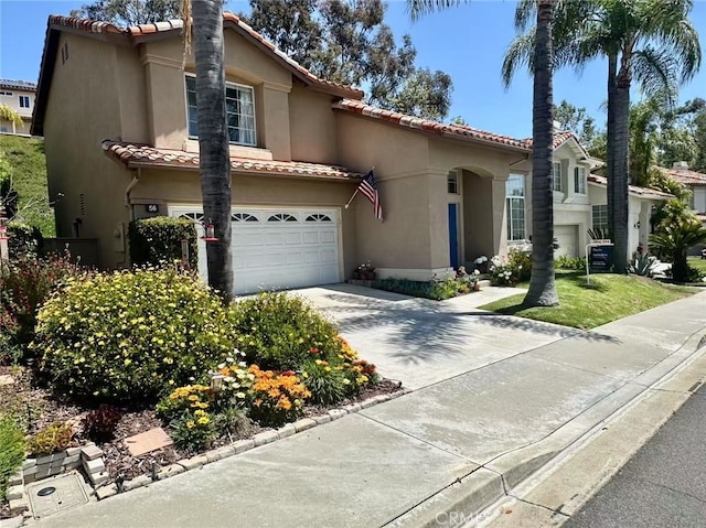 mediterranean / spanish house with a tiled roof, central air condition unit, concrete driveway, an attached garage, and stucco siding