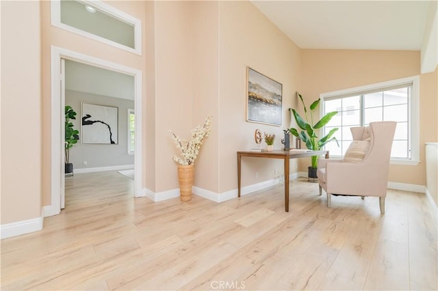 sitting room with baseboards, light wood finished floors, and lofted ceiling